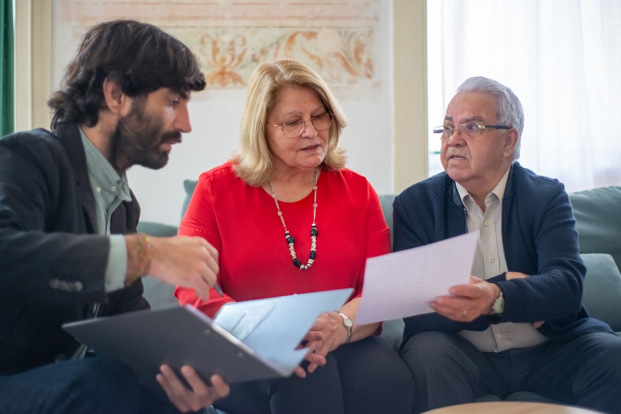 Acceuil Senior couple consulting with a professional advisor, discussing documents indoors.