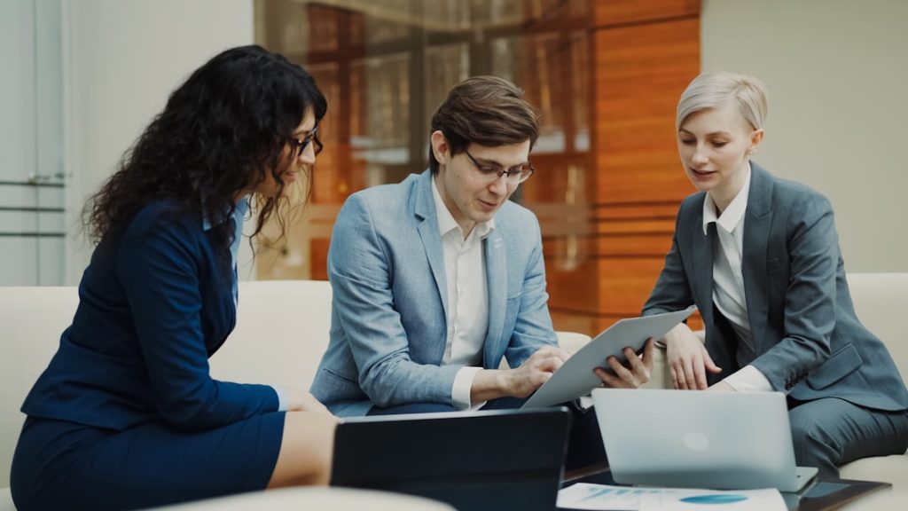 Acceuil Businessman talking and duscussing future contract with female business partners sitting on couch in meeting room indoors